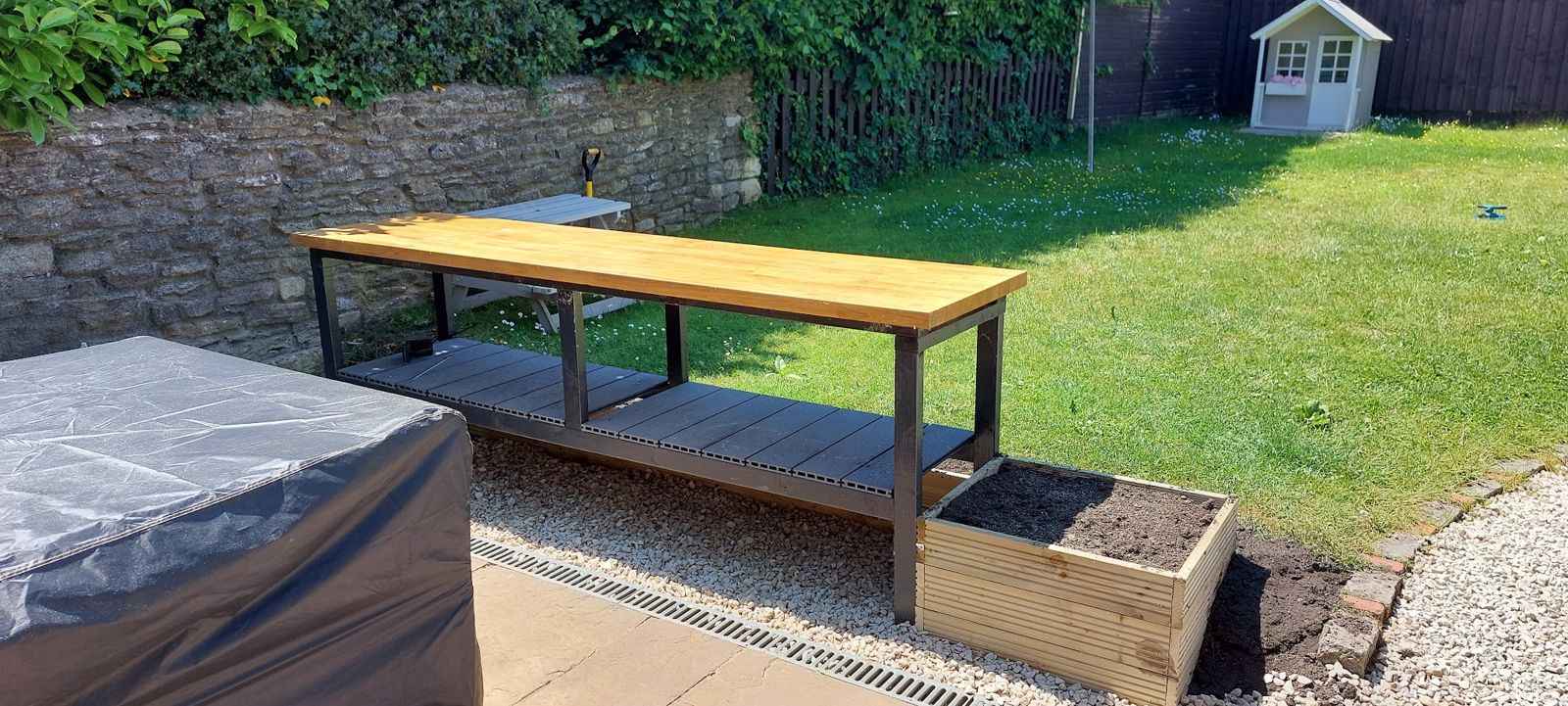 Garden bench with a grey slatted frame and timber top beside a timber planter