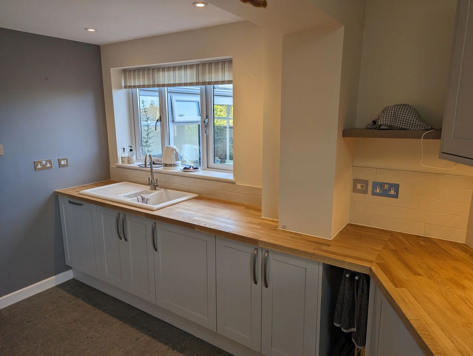 Kitchen with grey shaker units, an oak worktop and a white sink under the window