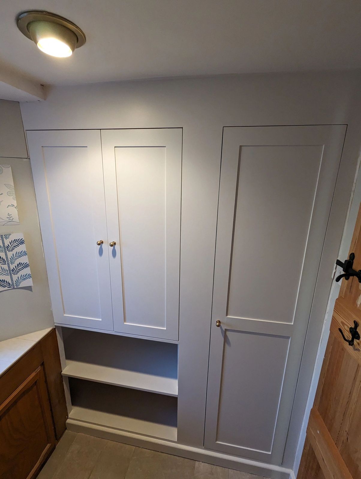 Painted fitted cupboards and wardrobe in an alcove, with an open shelf